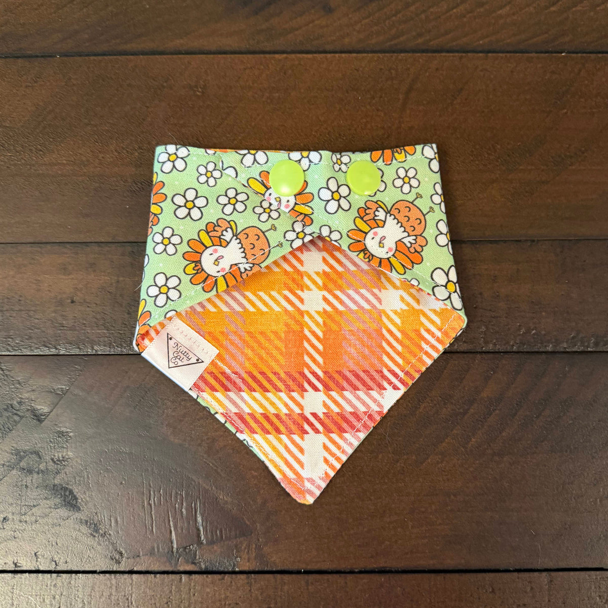 Groovy Turkeys pet bandana showing an orange, pink, and cream plaid reverse and bright green snaps.