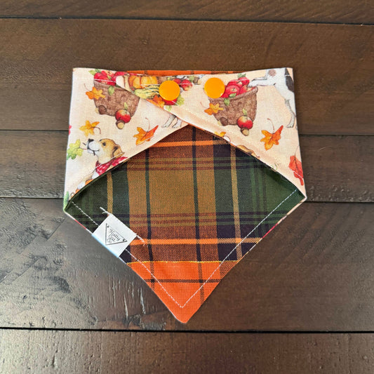 Cream pet bandana with dogs, autumn leaves, and a red wagon with a dog and pumpkins in it.