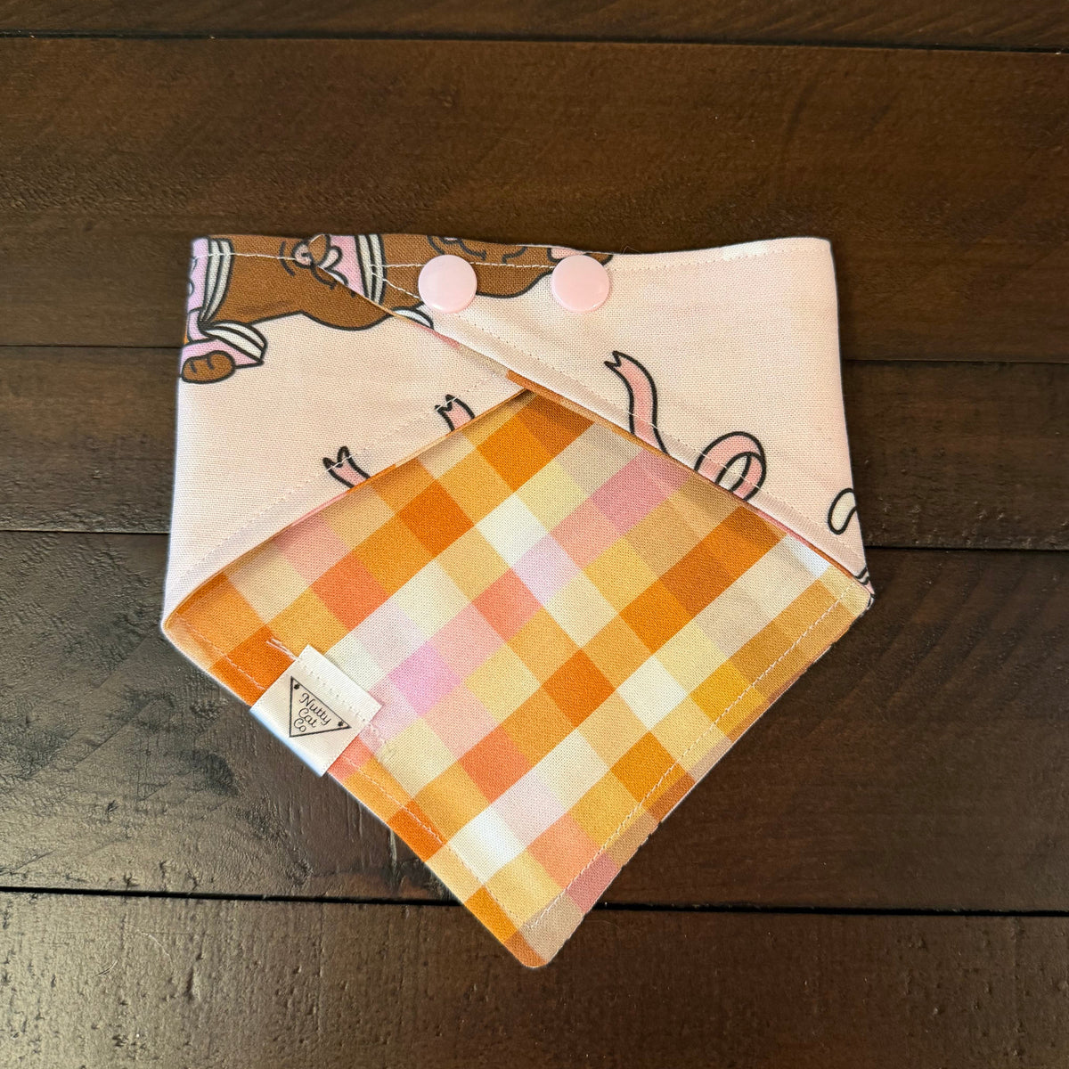 Bookish Fall Cats pet bandana showing an orange, yellow, and pink gingham reverse and light pink snaps.