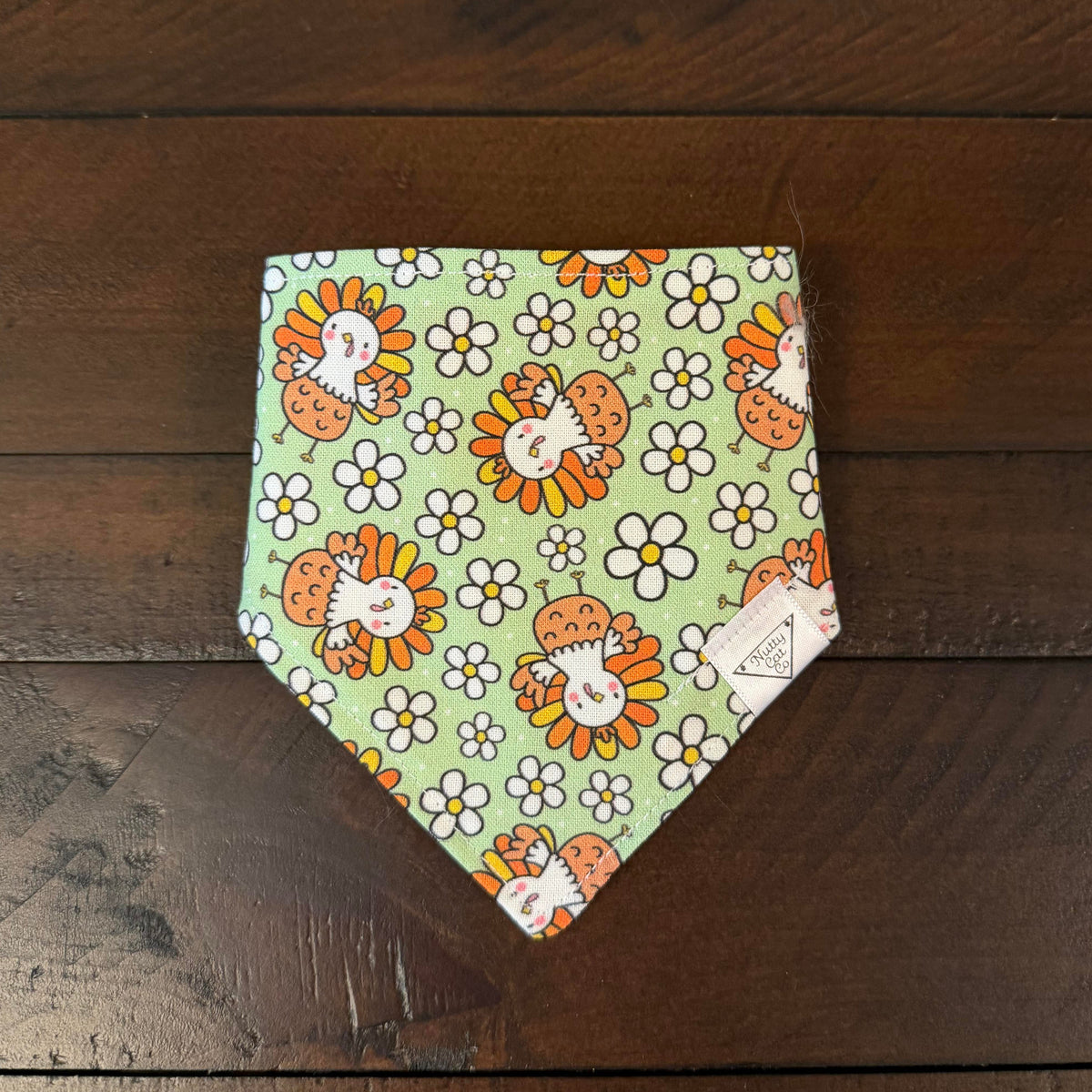 Light green pet bandana with smiling cartoon turkeys and white daisies.