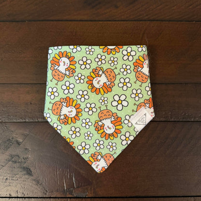 Light green pet bandana with smiling cartoon turkeys and white daisies.