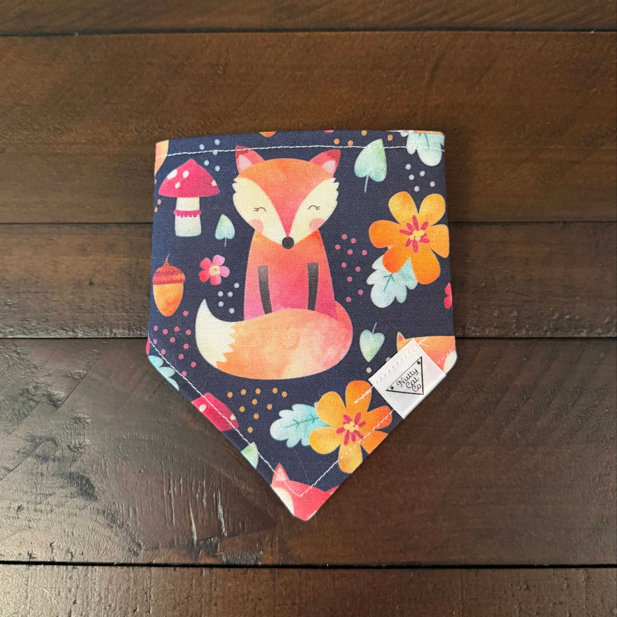 Navy pet bandana with an orange fox, colorful flowers, mushrooms, acorns, and leaves.