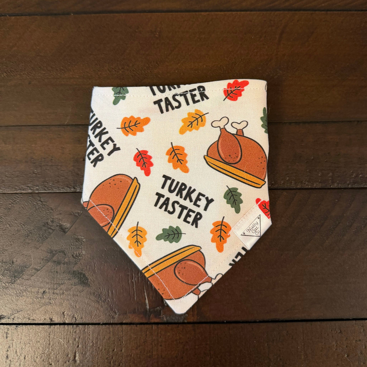 Cream pet bandana with roast turkeys, colorful autumn leaves, and the words Turkey Taster.
