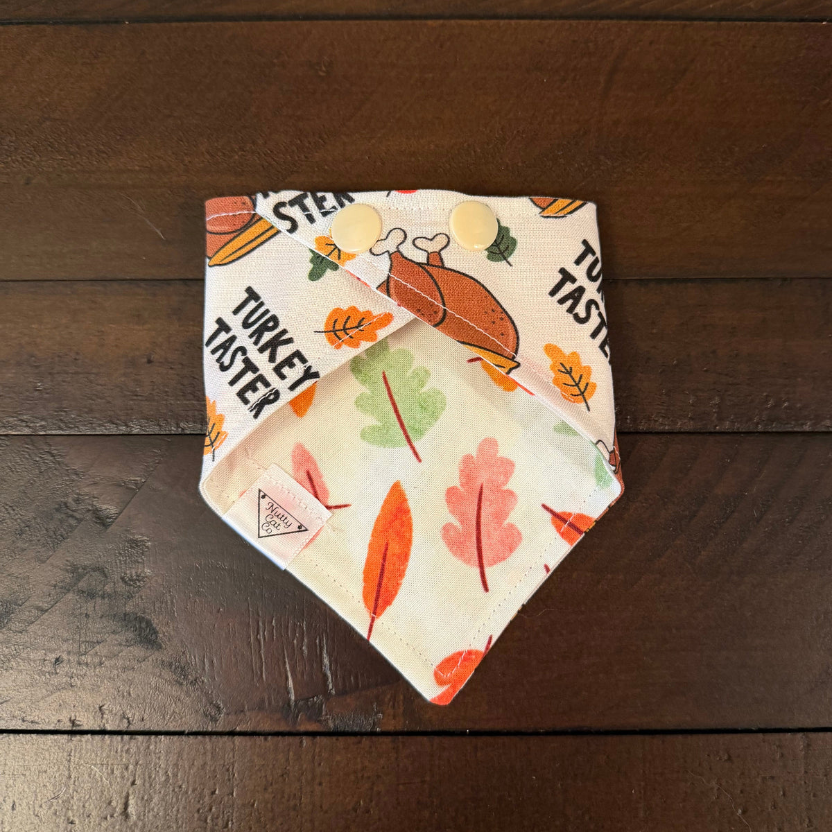 Turkey Taster pet bandana showing a multicolored autumn leaf reverse and cream snaps.