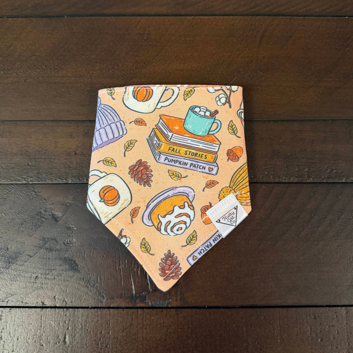 Peach pet bandana with autumn books, mugs, knit hats, cinnamon rolls, hot chocolate and pinecones.