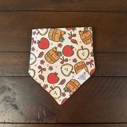 Cream pet bandana with red apples, apple slices, fruit baskets, bows, and small flowers.