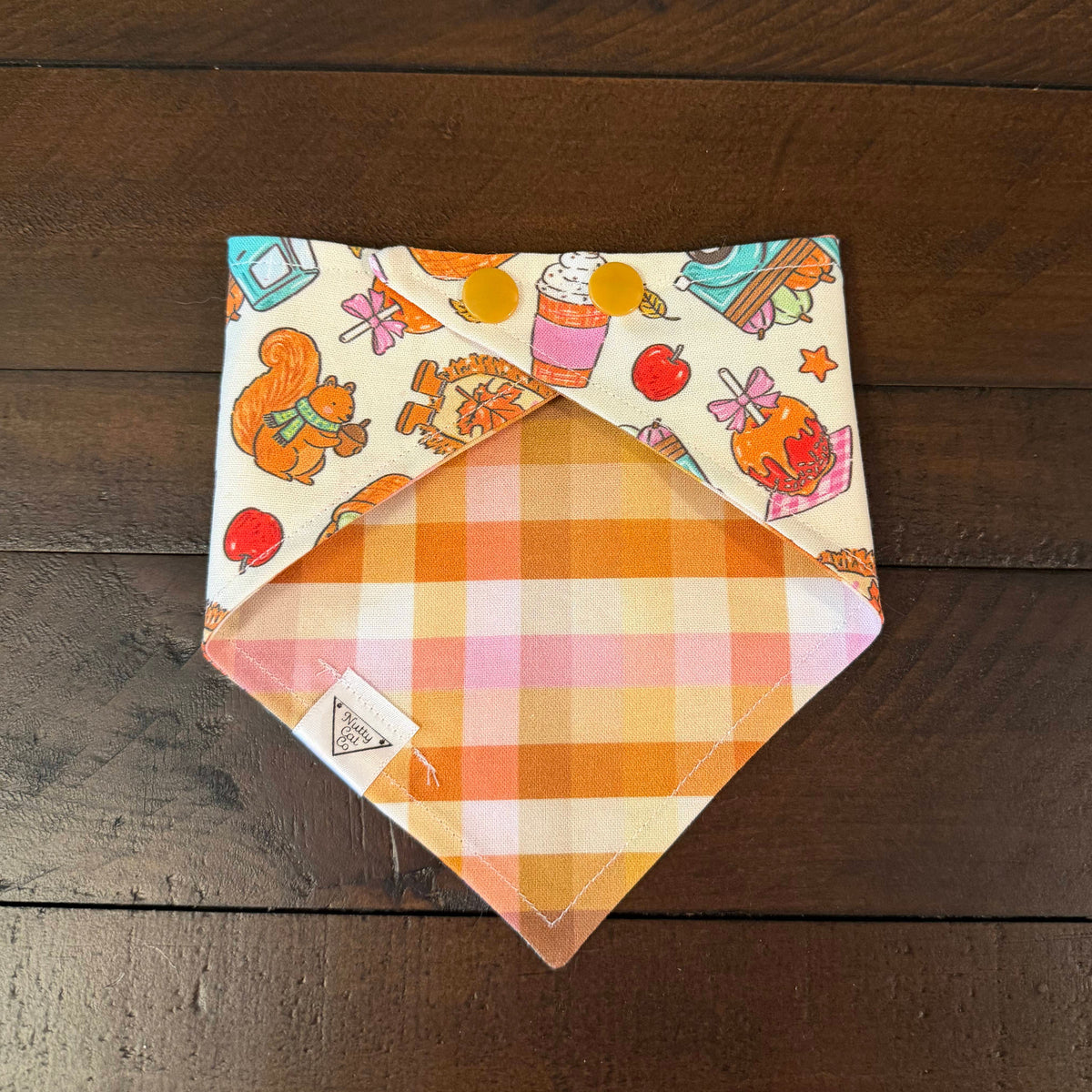 Woodland Farm pet bandana showing an orange, pink, and cream gingham reverse with tan snaps.